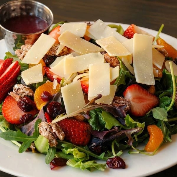Fresh salad with mixed greens, strawberries, mandarin oranges, pecans, dried cranberries, and shaved cheese.