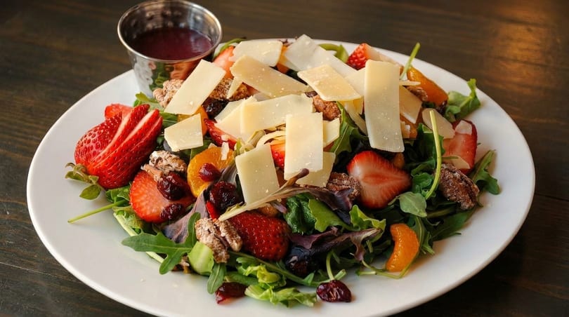 Fresh salad with mixed greens, strawberries, mandarin oranges, pecans, dried cranberries, and shaved cheese.